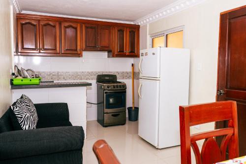 a kitchen with a white refrigerator and a stove at BNB Tropical Island Aparthotel - Corales del Sur, Santo Domingo Este in Santo Domingo