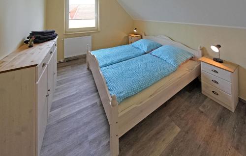 a bedroom with a bed with blue sheets and a wooden floor at Amazing Apartment In Mirow With Kitchen in Mirow