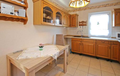 una cucina con armadi in legno, tavolo e finestra di Cozy Apartment In Wesenberg With Kitchen a Wesenberg