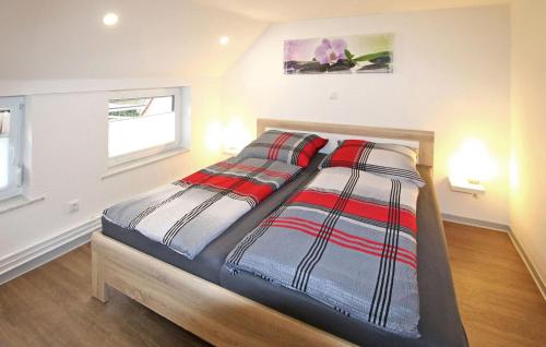 Schlafzimmer mit einem Bett mit roter und schwarzer gestreifter Bettwäsche in der Unterkunft Awesome Home In Penzlin With Kitchen in Penzlin