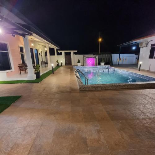 a swimming pool in the middle of a courtyard at night at Anzra Home2stay in Kertih