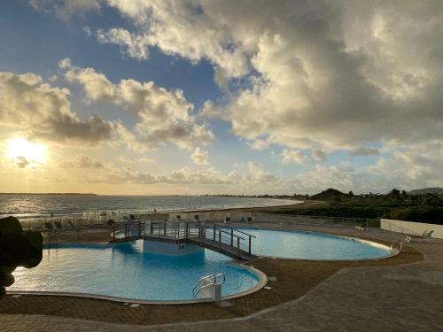 una piscina junto a una playa con el océano en Sunset View & Ocean Breeze, en Saint Martin