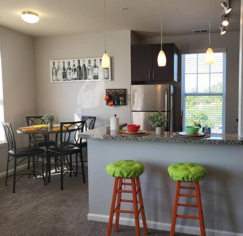 una cocina con una barra con taburetes verdes. en Luxury 1BR/1BA w/ Top Amenities in Prime Location, en Fort Wayne