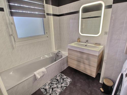une salle de bain avec une baignoire, un lavabo et un miroir dans l'établissement Charmant Appart avec Garage et Terrasse au Coeur de Colmar, près de la Route des Vins d'Alsace - FR-1-722-6, à Colmar