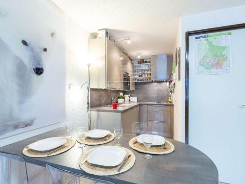 une cuisine avec une table avec des assiettes et un ours polaire sur le mur dans l'établissement Studio 4 pers. avec garage, balcon et navette, proche commerces et téléphérique à Saint-Lary-Soulan - FR-1-296-497, à Saint-Lary-Soulan