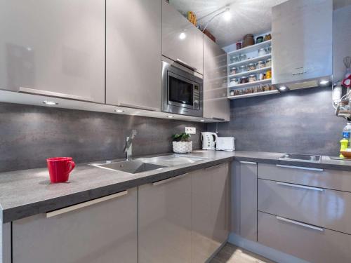 une cuisine avec des armoires blanches et un évier dans l'établissement Studio 4 pers. avec garage, balcon et navette, proche commerces et téléphérique à Saint-Lary-Soulan - FR-1-296-497, à Saint-Lary-Soulan