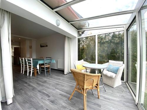 une véranda avec une table et des chaises sur une terrasse dans l'établissement Maisonnette à Perros-Guirec près de la plage avec parking - FR-1-368-415, à Perros-Guirec