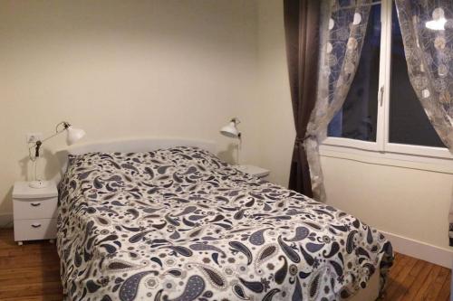 ein Bett mit einer schwarzen und weißen Bettdecke und einem Fenster in der Unterkunft Cosy Home in Paris 15 in Paris