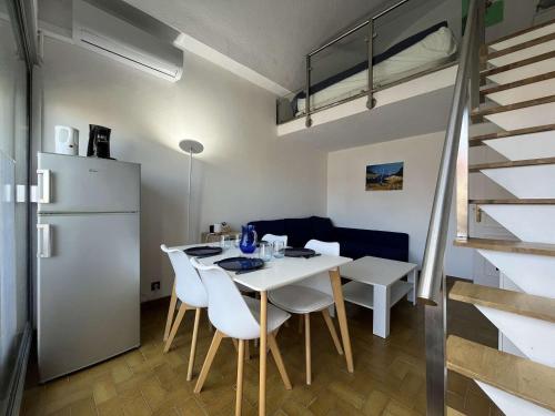 une cuisine et une salle à manger avec une table et des chaises blanches dans l'établissement Studio mezzanine 4 pers, climatisé, centre Gruissan - FR-1-229-879, à Gruissan