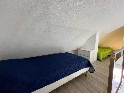 - une chambre avec un lit bleu et un oreiller vert dans l'établissement Studio mezzanine 4 pers, climatisé, centre Gruissan - FR-1-229-879, à Gruissan