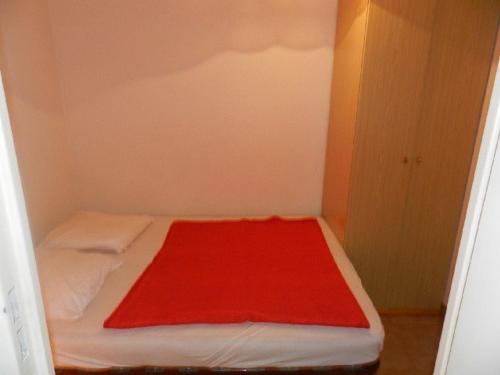 Cette petite chambre comprend un lit avec une couverture rouge. dans l'établissement Appartement cocooning 4 pers, accès plage et commerces, parking privé, ménage inclus - FR-1-251-665, à Bormes-les-Mimosas