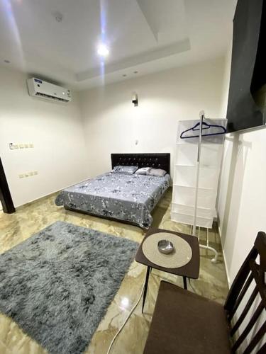a bedroom with a bed and a table and rug at استديو في حي النهضة - دخول ذكي ٤أ in Buraydah