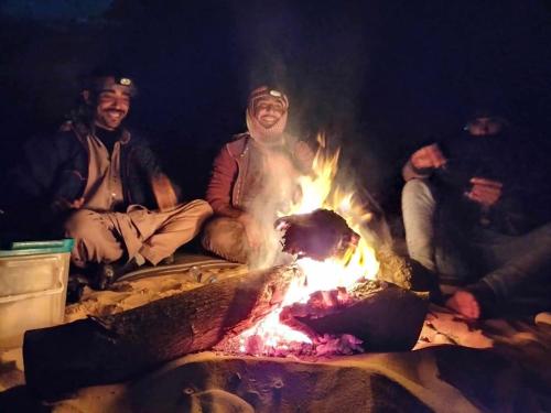 a group of people sitting around a fire at White desert Egypt safari in Bawati