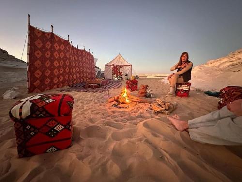 a group of people sitting around a fire in the sand at White desert Egypt safari in Bawati
