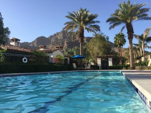 een zwembad met palmbomen en een huis bij Resort King Studio with Private Balcony 064622 in La Quinta