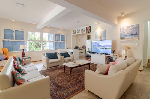 a living room with white furniture and a flat screen tv at Hospedaria Conceitual in Florianópolis