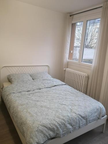 Bett in einem weißen Zimmer mit Fenster in der Unterkunft Studio cosy tout confort proche aéroport et Paris in Choisy-le-Roi