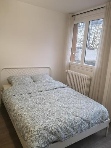 un lit dans une chambre blanche avec une fenêtre dans l'établissement Appartement cosy à 10mn de l'aéroport d'Orly et proche de Paris, à Choisy-le-Roi