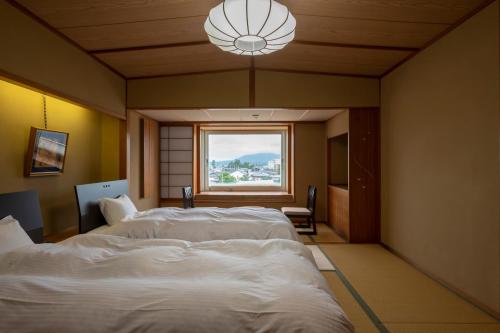 two beds in a room with a window at Kaike Tsuruya in Yonago