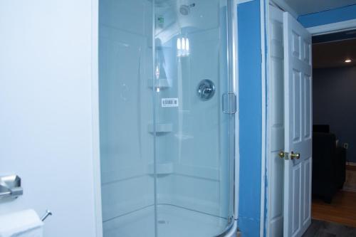 a shower with a glass door in a bathroom at Cosy Basement Apartment on the East side. in Saint John