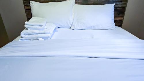 ein weißes Bett mit weißer Bettwäsche und Handtüchern darauf in der Unterkunft Cosy Basement Apartment on the East side. in Saint John