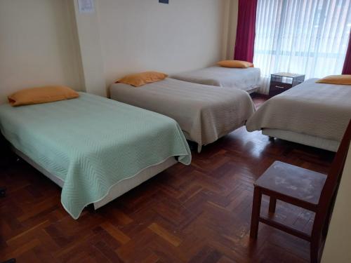 a room with three beds and a wooden floor at Hostal Venegas in Copacabana