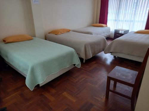 a room with three beds and a wooden floor at Hostal Venegas in Copacabana