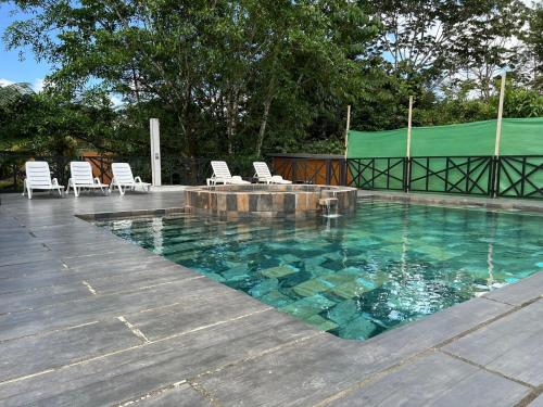 a swimming pool with chairs and a table and water at Residencias Arenal in Fortuna