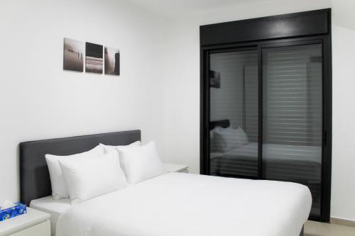 1 dormitorio con cama blanca y armario de cristal en Suite Apartment #17 By Hashdera Eilat, en Eilat