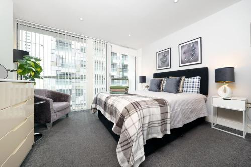 um quarto com uma cama, uma cadeira e uma janela em Cobalt Point 2 em Londres