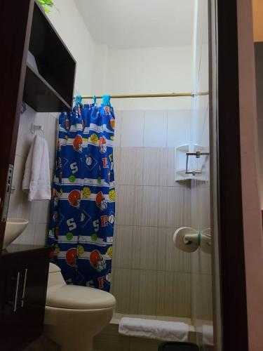 a bathroom with a toilet and a shower curtain at Alojamiento Piquero Azul in Puerto Ayora