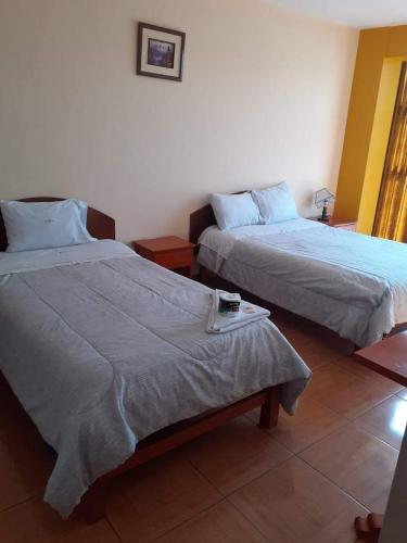 Un dormitorio con 2 camas y una mesa con una toalla. en Hostal Vanguts, en Huancayo