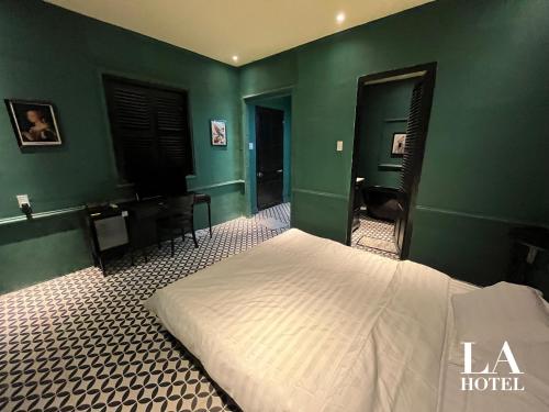um quarto com uma cama branca e paredes verdes em La Hotel em Trung An