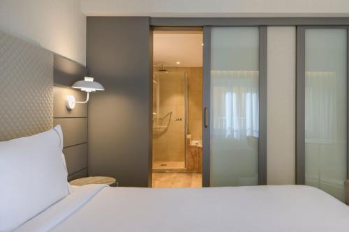 1 dormitorio con cama blanca y ducha en AC Hotel Carlton Madrid by Marriott en Madrid