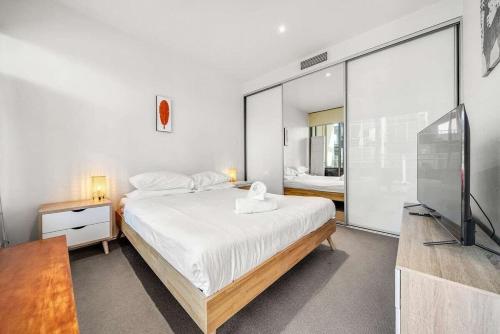 a bedroom with a large bed and a television at Canberra Lakefront 2-Bed with Pool, Gym & Parking in Kingston 