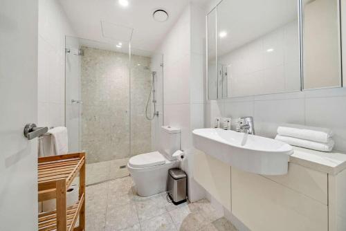 a white bathroom with a sink and a toilet at Canberra Lakefront 2-Bed with Pool, Gym & Parking in Kingston 