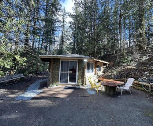 a small cabin with a table and chairs in the woods at Cabin in the woods @ Cultus Lake in Chilliwack
