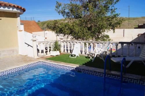 a swimming pool with two chairs next to a house at 3 bedrooms chalet with private pool terrace and wifi at La Almarcha in La Almarcha