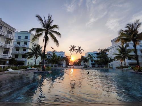 a large swimming pool with palm trees and buildings at Stella Marina Boutique Hotel in Phu Quoc