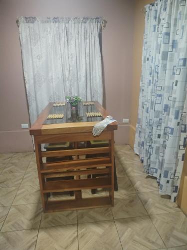 a wooden table in front of a window with curtains at Departamento Yaqui in Aguas Claras