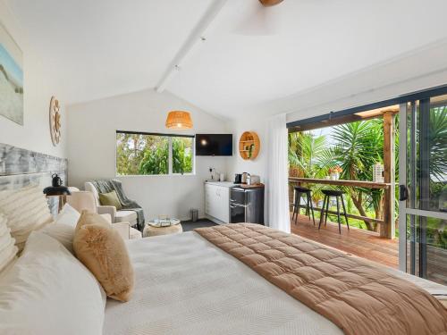 Country Idyll - Sandspit Holiday Cottage في Sandspit: غرفة نوم مع سرير كبير وغرفة معيشة