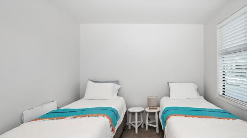 two twin beds in a room with a window at Residence De La Mer - Orewa Holiday Home in Orewa
