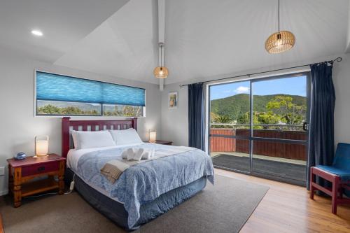 a bedroom with a bed and a large window at Waimarama Hideaway - Waikawa Holiday Home in Waikawa