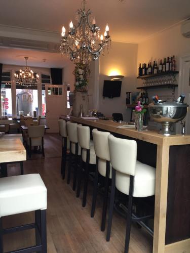a restaurant with a bar with white bar stools at Hotel Montfoort in Montfoort