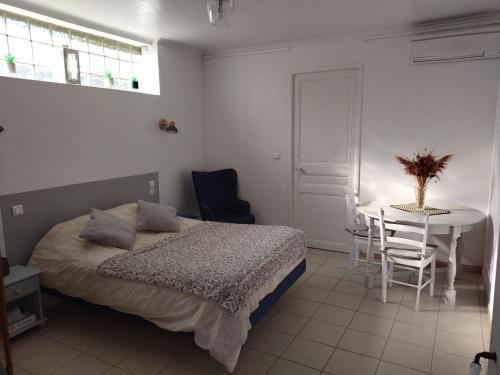 een slaapkamer met een bed en een tafel en stoelen bij Studio indépendant dans charmante bastide in Mallemort