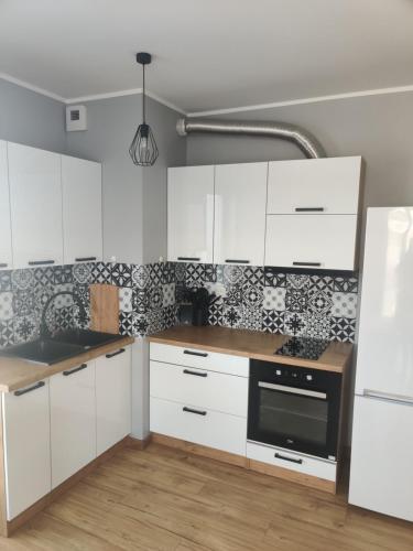 uma cozinha com armários brancos e electrodomésticos pretos em Apartament Perła Kutna em Kutno