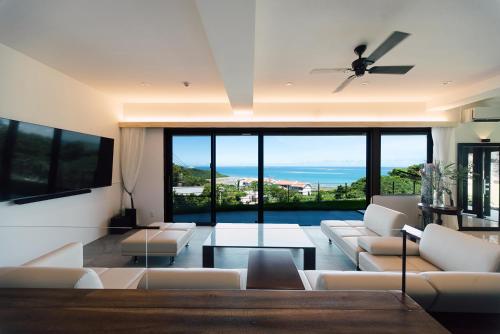a living room with white furniture and a view of the ocean at Villa CHINENBLUE 日常を忘れコバルトブルーの海と過ごす究極の休日 in Kudeken