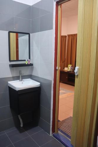 een badkamer met een wastafel en een spiegel bij Bunga Raya Resort Parit Buntar in Parit Buntar