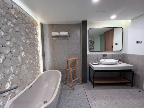 a bathroom with a tub and a sink and a mirror at Luminor Hotel Legian Seminyak - Bali in Legian