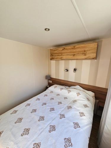 een slaapkamer met een bed met een wit dekbed bij Mobil-Home Le Bosc 5 personnes in Le Bosc